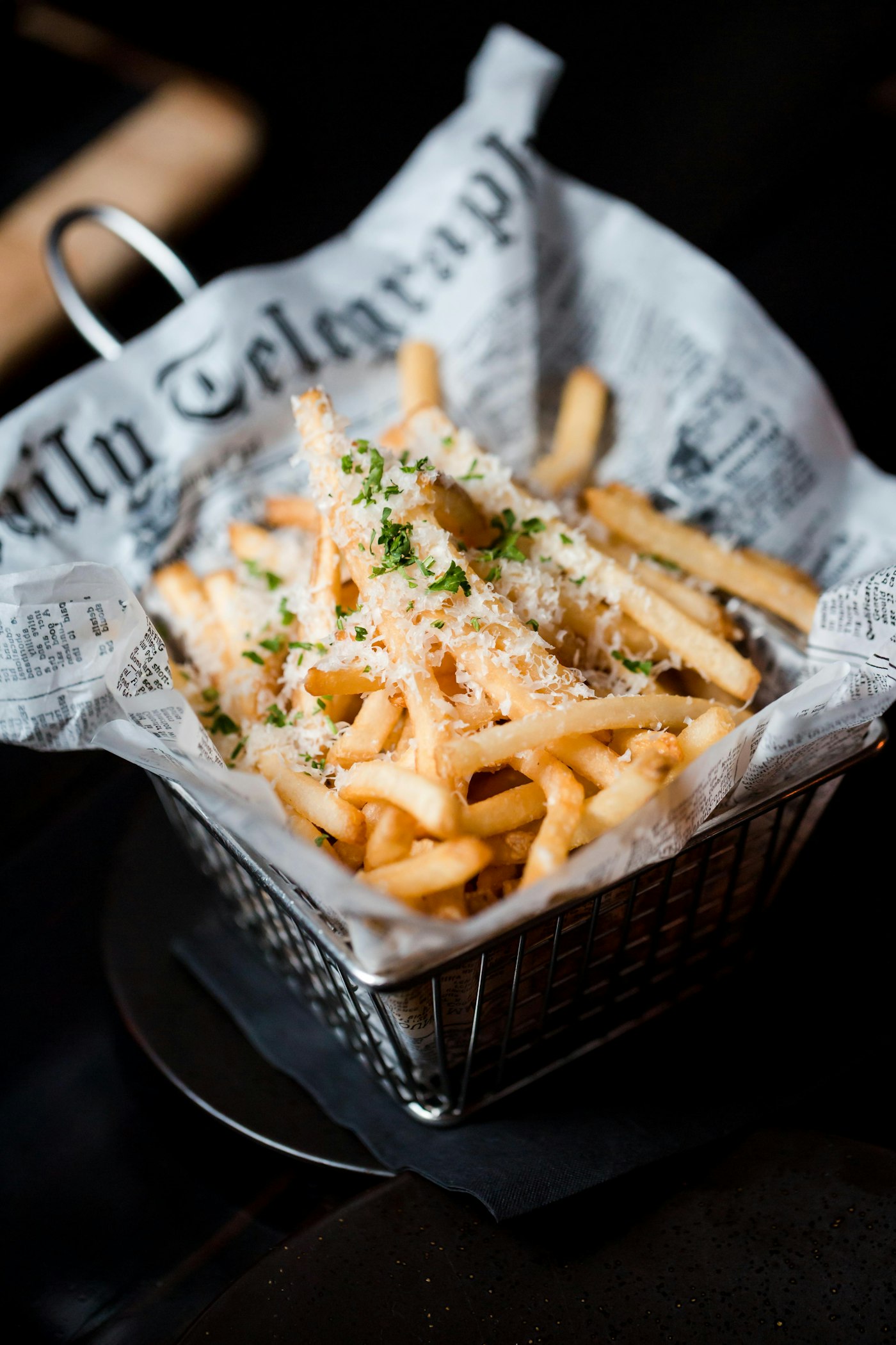 Loaded fries with herbs in a newspaper-lined basket