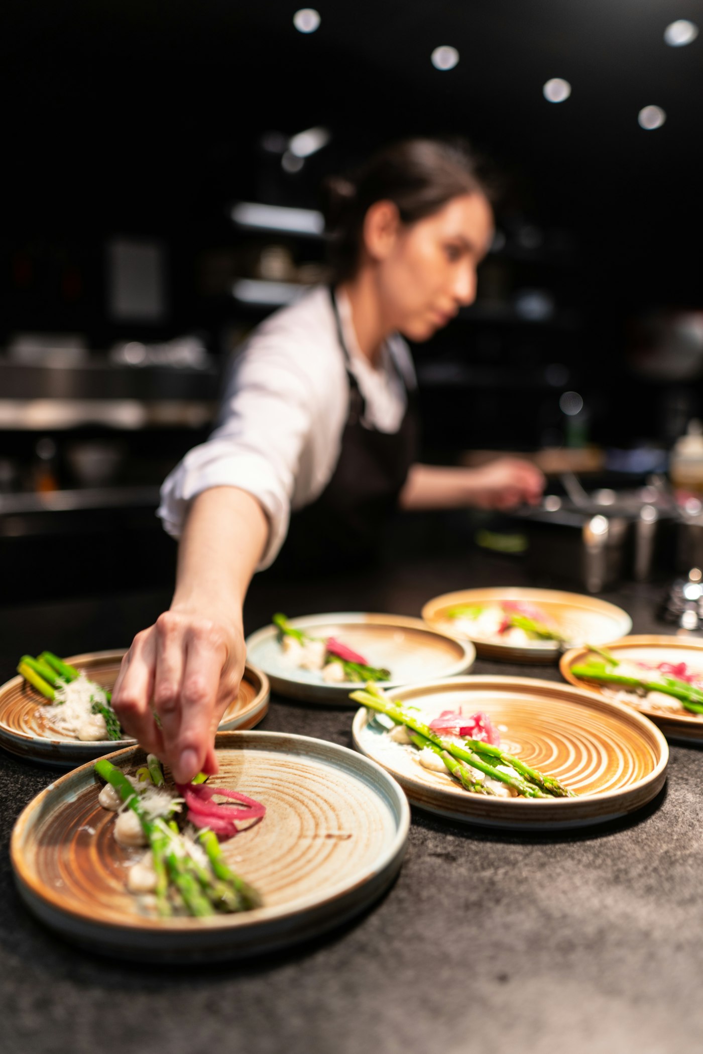 Chef plating several dishes at the pass