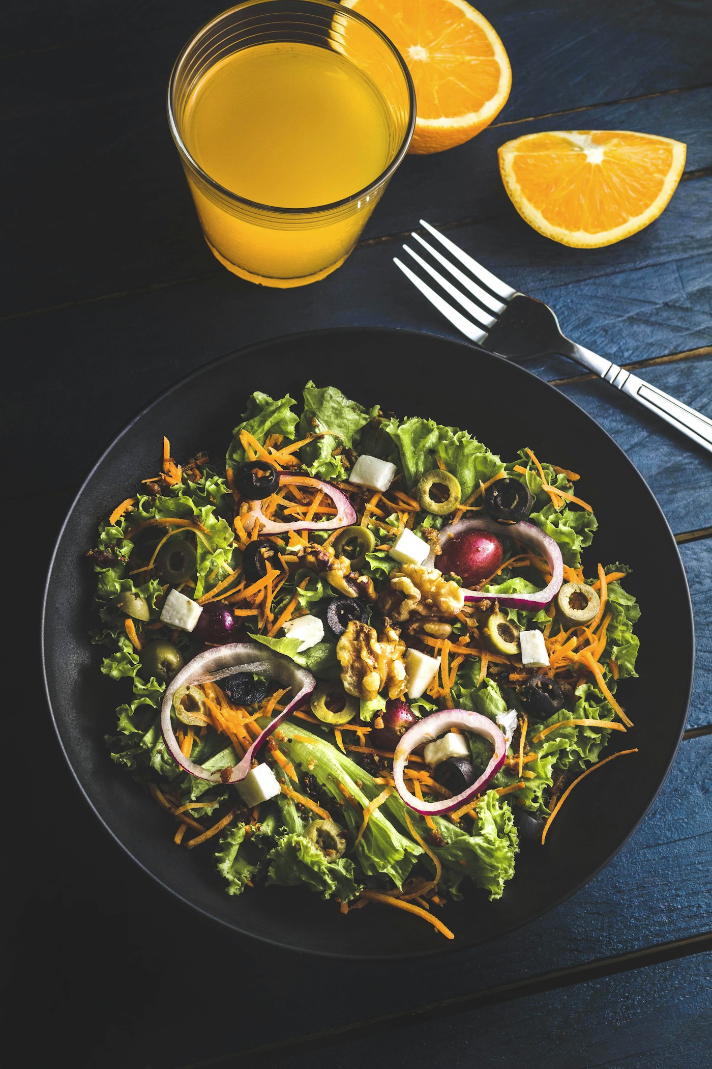 Charred vegetables, greens and toasted seeds on a dark plate