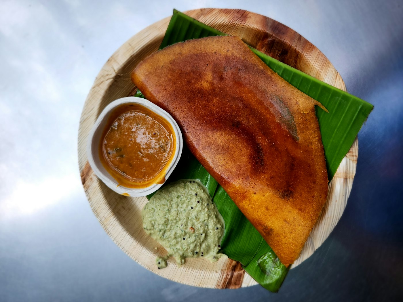 Dosa folded over chutney on a banana leaf